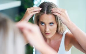 Devojka gleda teme glave u ogledalu