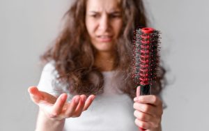 Devojka drzi cetku sa opalom kosom na njoj