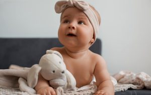 Beba devojcica sa trakom na glavi i plisanim zekom